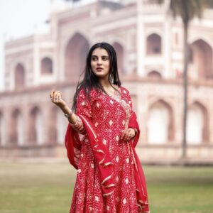 Woman in red traditional attire at Humayun's Tomb, Delhi, India, showcasing cultural heritage.