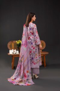 Woman in a floral traditional dress stands elegantly in an indoor setting.