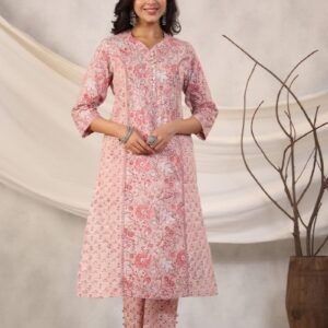 Woman poses in a pink floral kurta and pants.