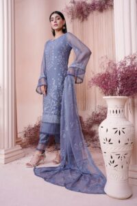 a woman in a blue dress standing next to a vase