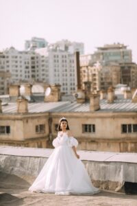 a woman in a white dress standing on a roof