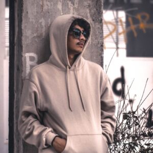men wearing a grey hoodie jacket leaning in a wall during daytime